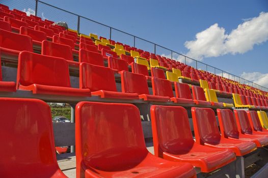 Red and yellow seats on a background of the sky with clouds.