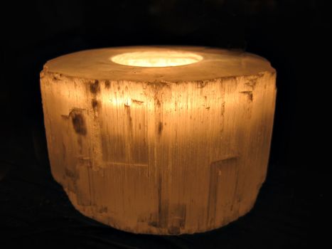 Glowing candle in a transparent holder with black background