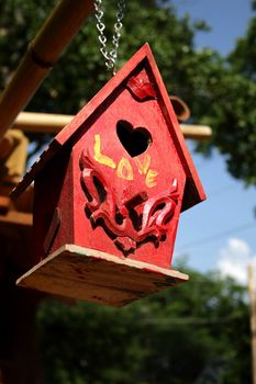 Red birdhouse hanging in a community garden