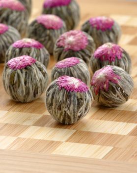 Several handsewn balls of flowering tea ion a bamboo counter.