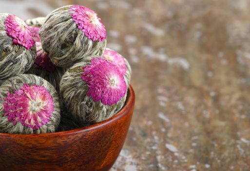 Several handsewn balls of flowering tea in a bamboo bowl.