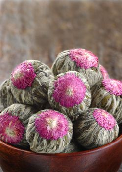 Several handsewn balls of flowering tea in a bamboo bowl.