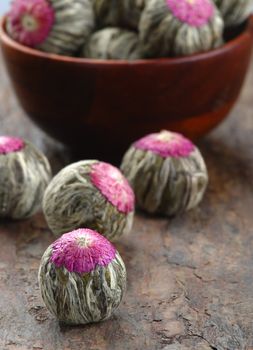 Several handsewn balls of flowering tea on a stone counter.