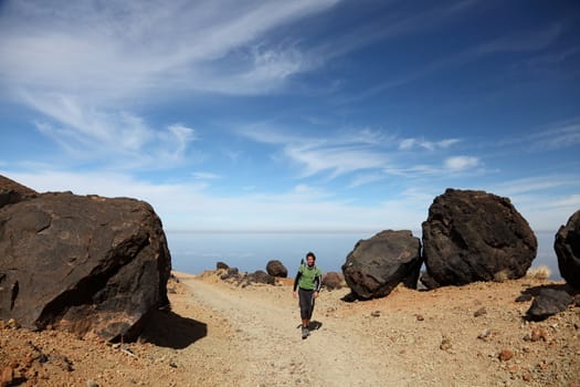 Hiking on Teide Tenerife. Man hiking / backpacking on Monta�a Blanca within the national park of Teide on Tenerife. A view of the hiking path at  showing many of the big black Teide eggs or in spanish: Los Huevos del Teide. Blue sky for copy space.