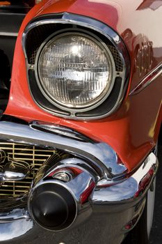 A closeup of the headlight and front bumper on a vintage car.