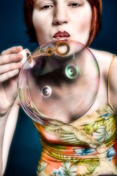 Red haired girl is trying to blow some big bubbles