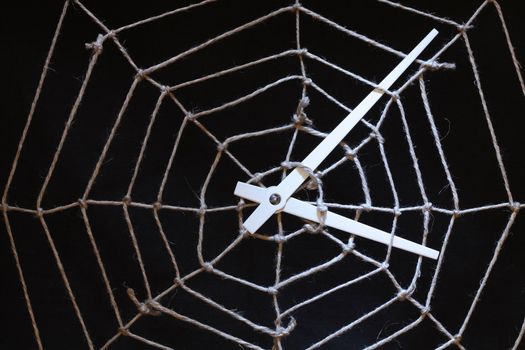 Conceptual background with web made from rope and clock hands on dark