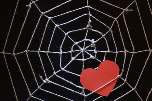 Conceptual background with web made from rope and red paper heart on dark