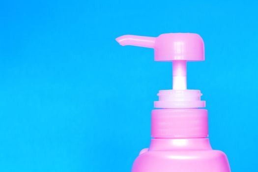 A pink plastic bottle of antibacterial blue liquid soap on a blue background