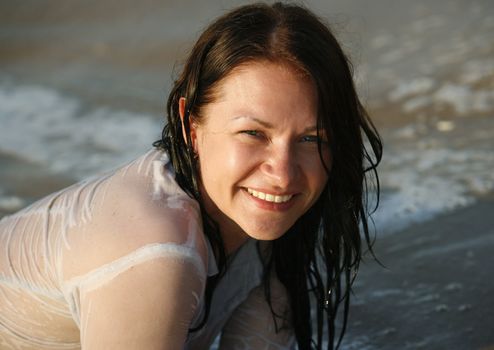 The happy girl in a wet dress at coast of the sea