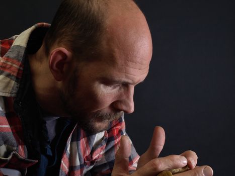 A man stares into his coffee cup, a deep expression on his face. Over black