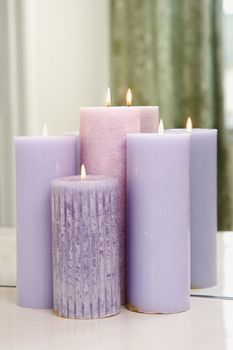 Group of purple candles burning in front of mirror.