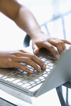 Asian/Indian young womans hands typing on laptop keyboard.