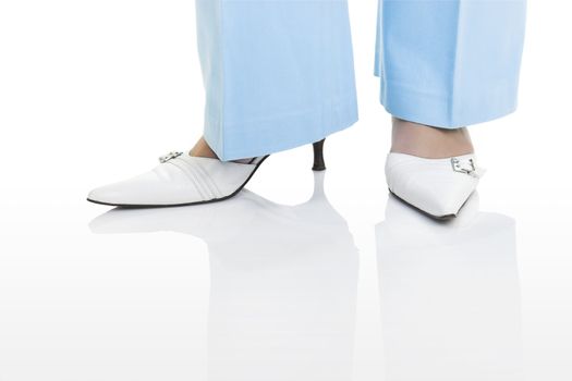 Woman legs with beautiful white shoes on a white background with reflection