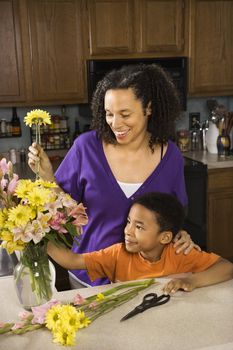 Portrait of young pregnant mother and son arranging flowers.