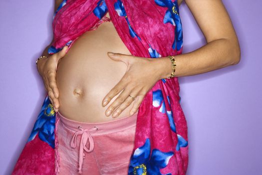 Close up portrait of expecting female with hands on stomach.