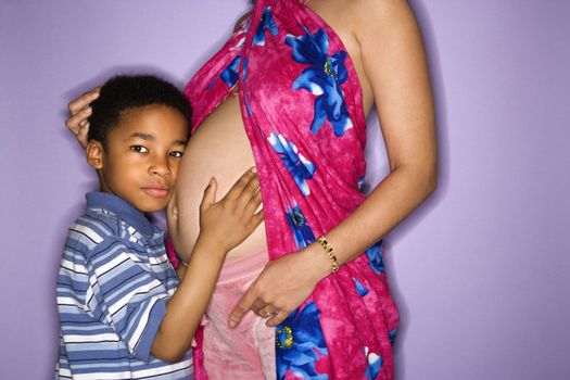 Portrait of expecting female with son listening to stomach.