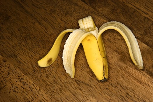 Still life of half eaten banana on wooden table.