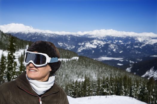 Caucasian middle-aged woman skier in goggles posing on mountain.