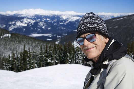 Caucasian senior man skier in goggles posing on mountain.
