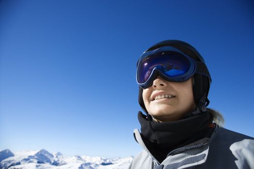 Caucasian teenage boy snowboarder wearing helmet and goggles on mountain.