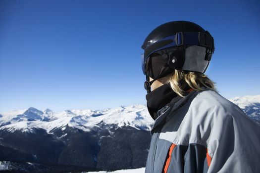 Caucasian teenage boy snowboarder wearing helmet and goggles on mountain.