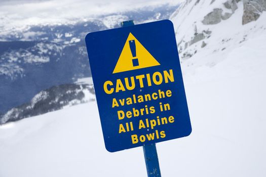 Snow ski resort caution sign on mountain side.