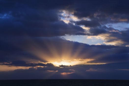 Sunbeams coming through clouds at sunrise over Maui, Hawaii, USA.