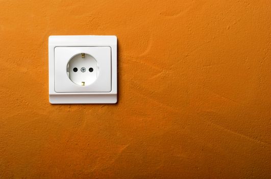 Electric wall plug at a orange wall 