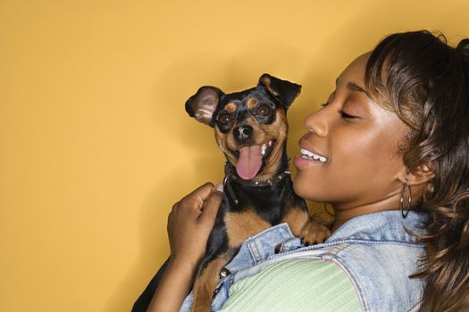 African American young adult female holding Miniature Pinscher dog.