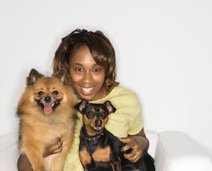 African American young adult female holding brown Pomeranian and Miniature Pinscher dogs.