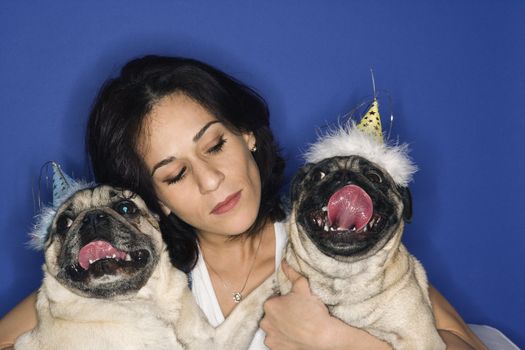 Caucasian prime adult female holding two Pug dogs.