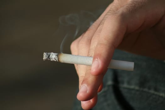 Close up of a hand holding a cigarette.