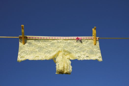 Clothes on washing laundry line, yellow lingerie, blue sky