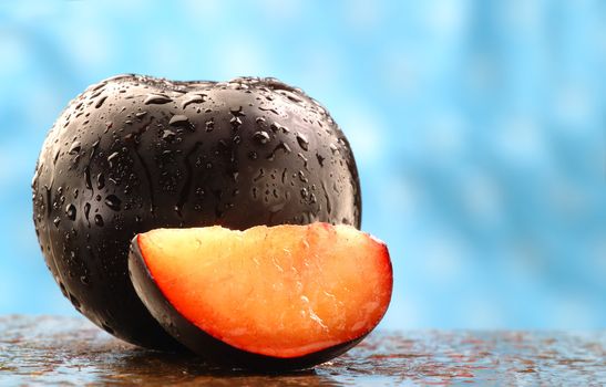 Fresh black plums on a stone counter.