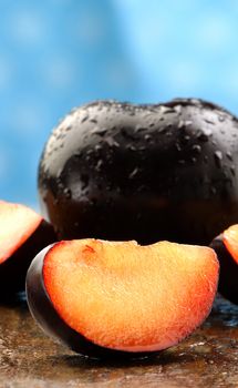 Fresh black plums on a stone counter.