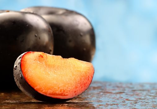 Fresh black plum slice on a stone counter.