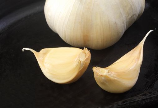 Whole head and cloves of garlic on black background.