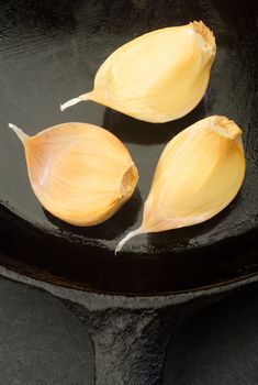 Cloves of garlic in a cast iron skillet.