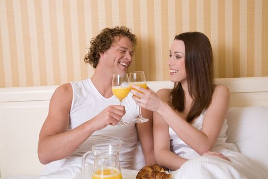 Lovely young couple enjoying a simple breakfast in bed
