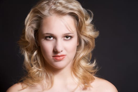 Beautiful young blond woman on black background