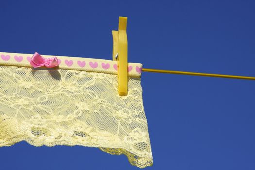 Clothes on washing laundry line, yellow lingerie, blue sky