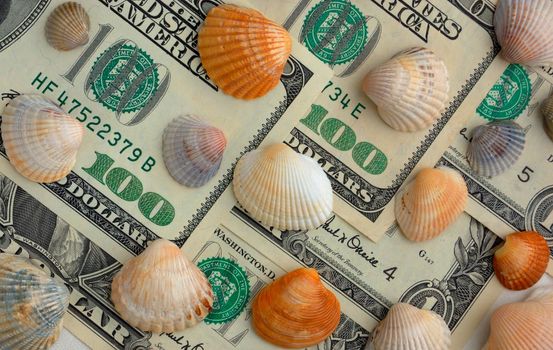 How mach is the summer travel? Close-up of 100 dollar bill and shells of different colors