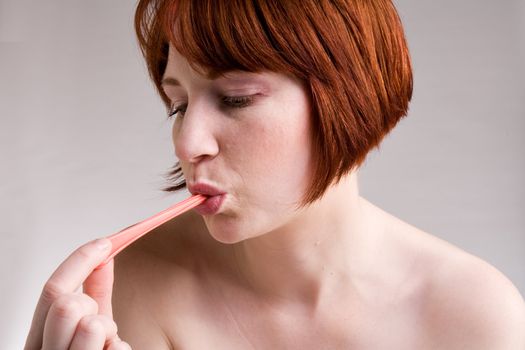 Red haired girl is eating fresh bubblegum