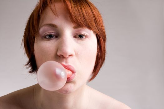 Red haired girl is eating fresh bubblegum