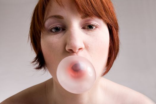 Red haired girl is eating fresh bubblegum