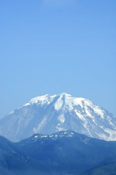 A vertical shot of Mount Rainier's peak from about 50 miles away, in summer.