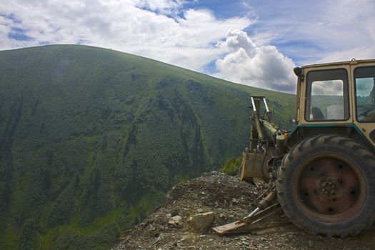 Part of a dredge on a background of a mountain landscape. The beautiful sky. Mountain on a background, cut up by rivulets and clefts