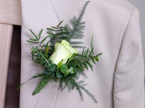 Groom's wedding suit with boutonniere made of rose and green leaves