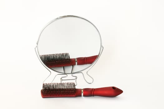 A round mirror and a hairbrush, isolated on a white background.